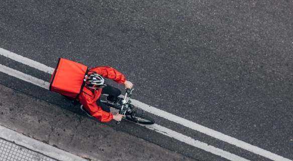 Image d'une personne réalisant une livraison sur un vélo au bord de la route