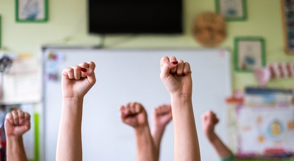 Enfants levant les bras points fermés dans une salle de classe